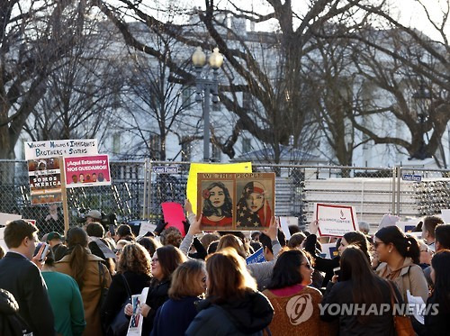 25일 백악관 앞에서 트럼프 대통령의 이민 정책에 항의하며 셰퍼드 페어리의 포스터로 만든 피켓을 든 시위자 [AP=연합뉴스]