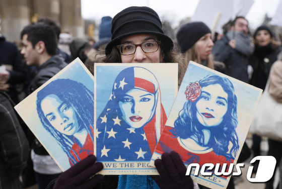 도널드 트럼프 미국 대통령에 반대하는 한 시위 참가자가 "우리가 국민이다"(We the people)고 적힌 3장의 피켓을 들고 있다. 각각 무슬림·여성·흑인을 상징한다. © AFP=뉴스1