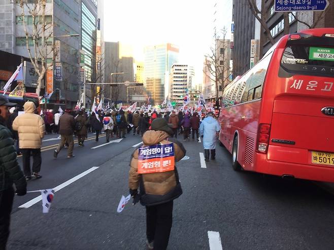 계엄령을 내리자고 주장하는 플래카드를 등에 멘 한 ‘태극기 집회’ 참가자가 시가행진을 하고 있다.