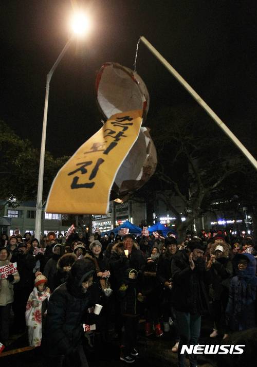 【제주=뉴시스】우장호 기자 = 정유년 정월대보름인 11일 오후 제주시청 종합민원실 앞 도로에서 박근혜 정권 퇴진 제주행동 주최로 열린 제주지역 16차 촛불집회에서 시민들이 대보름맞이 '즉각퇴진'이라고 써진 박을 터뜨리고 있다.  2017.02.11.   woo1223@newsis.com