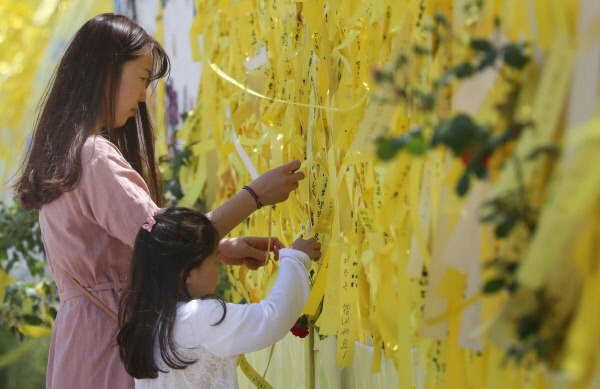 14일 세월호가 거치된 목포신항에서 시민들이 미수습자의 수습을 기원하며 노란리본을 매달고 있다.  연합뉴스