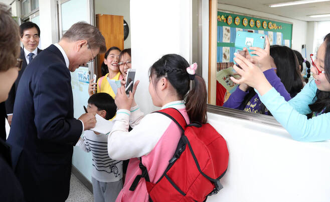 문재인 대통령이15일 서울 은정초등학교에서 행사를 마친 뒤 복도에서 학생들에게 사인을 해주고 있다. 청와대사진기자단