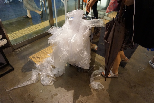 지난 7일 서울 마포구의 한 매장 입구. 건물 출입구에 비치된 우산 비닐 커버와 쓰레기 봉투에 버려진 우산 비닐 커버가 가득하다. [사진=박로명 기자/dodo@heraldcorp.com]