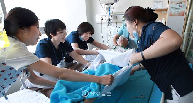 간호사들이 목욕을 위해 환자를 목욕침대로 옮기고 있다. [조문규 기자]
