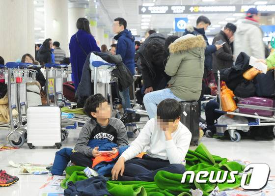제주지역에 많은 눈이 내려 항공기 전편이 결항된 24일 제주국제공항에서 관광객들이 바닥에 담요를 깔고 쉬고 있다.2016.1.24/뉴스1 © News1 이석형 기자