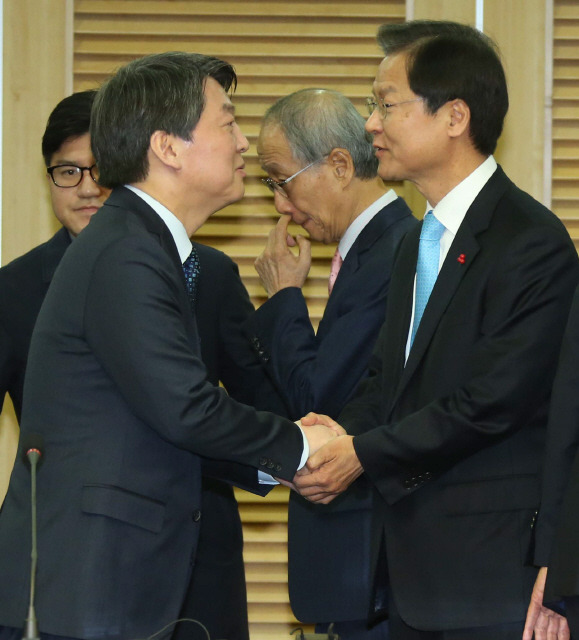 안철수 국민의당 인재영입위원장(왼쪽)과 천정배 국민회의 창당준비위원장이 25일 오전 국회 의원회관에서 통합선언을 한 뒤 악수하고 있다. 뒤편 가운데는 윤여준 국민의당 공동창당준비위원장.