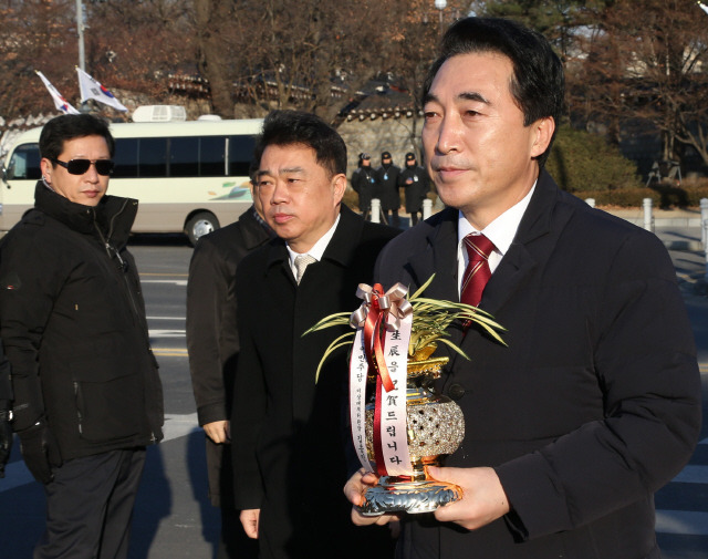 더불어민주당 김종인 비상대책위원장의 비서실장인 박수현 의원이 2일 오후 청와대 분수대광장에서 김 위원장이 박근혜 대통령에게 보내는 생일 축하난을 들고 청와대로 향하고 있다.