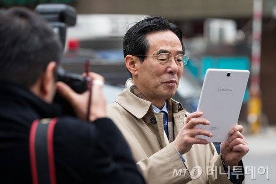 홍창선 더불어민주당 공천관리위원장이 8일 서울 여의도 새누리당사 앞에서 공천 탈락자의 시위를 자신의 태블릿PC로 촬영하고 있다. 2016.3.8/뉴스1  <저작권자 © 뉴스1코리아, 무단전재 및 재배포 금지>