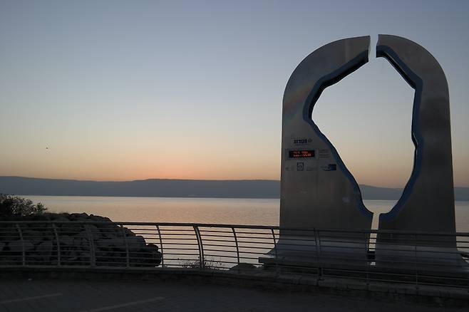 갈릴리 호숫가에 세워진 조각상. 가운데 뚫린 구멍이 갈릴리 호수의 모양이다. 북쪽 헤르몬산에서 흘러온 강이 사해를 거쳐 남쪽 요르단강으로 내려간다. 호수 건너 산 위로 여명이 비친다.