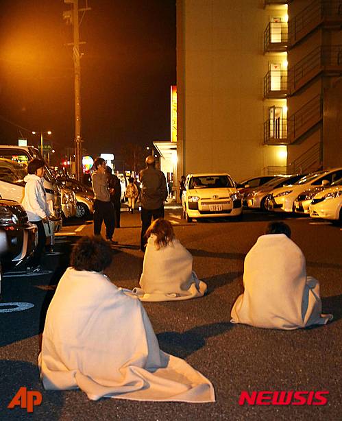Stranded people wrap themselves in blankets outside a hotel after an earthquake in Kumamoto, southern Japan, Thursday, April 14, 2016.  A powerful earthquake with a preliminary magnitude of 6.4 has struck southern Japan, collapsing walls and a number of houses.  (Kyodo News via AP) JAPAN OUT, MANDATORY CREDIT