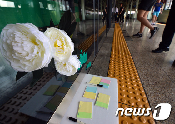 30일 오전 서울 광진구 구의역 9-4번 승강장에서 사고를 당한 김모(19)씨를 추모하는 국화와 포스트잇이 붙어 있다. 김 씨는 지난 28일 오후 지하철 2호선 구의역의 고장난 안전문(스크린도어)을 고치다 승강장에 들어오는 열차와 스크린도어 사이에 끼여 숨졌다. 2016.5.30/뉴스1 © News1 최현규 기자