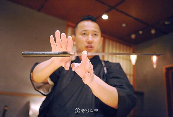 교텐이 칼을 들어보이며 설명을 하고 있다.