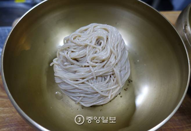 육수를 붓기 전의 냉면. 면은 허연 편이고, 바닥엔 통 들깨가 몇 알 보인다.