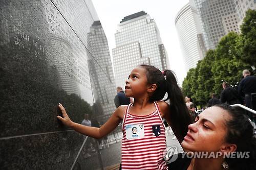 9·11 테러로 순직한 경찰 할아버지를 둔 여성이 딸과 함께 기념물에서 고인의 이름을 찾는 모습 [AFP=연합뉴스]