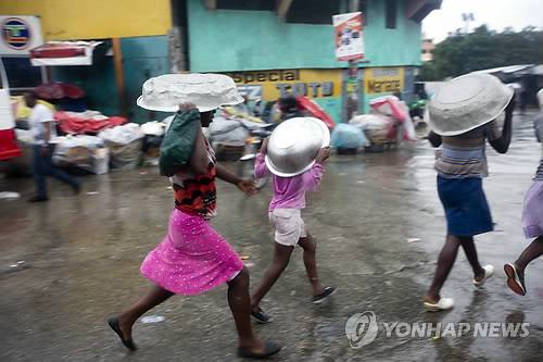 "비 막는 덴 대야만 한 게 없어"  (포르토프랭스 AP=연합뉴스) 초강력 허리케인 '매슈'가 강타한 카리브해 빈국 아이티의 수도 포르토프랭스에서 4일(현지시간) 주민들이 비를 피하려 대야를 머리에 쓰고 걷고 있다. 이날 아이티에서는 매슈의 영향으로 최소 3명이 숨지거나 실종됐으며 수많은 가옥이 파손됐다.