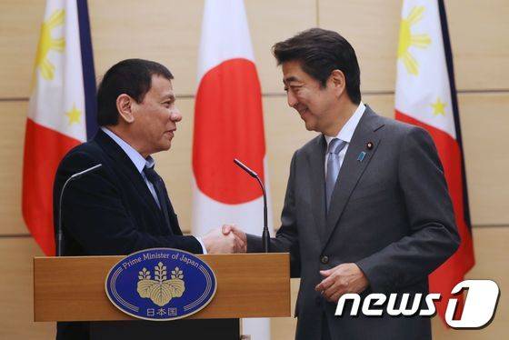 일본을 방문한 로드리고 두테르테 필리핀 대통령이 26일 도쿄 총리 공관에서 열린 기자회견에서 아베 신조 일본 총리와 악수를 나누고 있다. © AFP=뉴스1