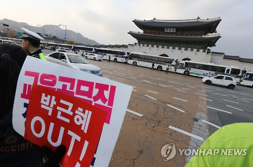 궁궐 앞에서      (서울=연합뉴스) 한상균 기자 = 박근혜 퇴진 촉구 3차 촛불집회가 12일 오후 서울 도심에서 열렸다.      한 시민이 경찰차벽으로 막힌 경복궁 앞에서 박근혜 아웃 팻말을 들고 있다.