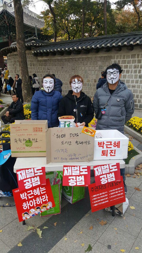 소규모 전자부품 가게를 운영하고 있는 김우겸 씨(오른쪽) 일행이 지난 12일 서울광장 앞에서 무료로 핫도그를 나눠주고 있다. [유준호 기자]