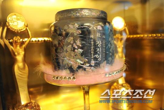 추모공원 장진영 유골함 옆에는 청룡영화상에서 받은 두 개의 여우주연상 트로피가 함께 전시되어 있다.