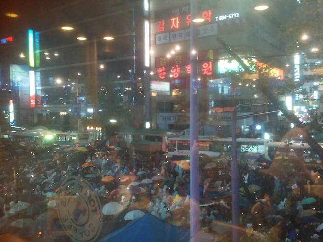 26일 저녁 부산 서면교차로에서 열린 박근혜 정권 퇴진 부산시국대회에 참석한 시민들이 우산을 쓰고 도로에 앉아 발언을 듣고 있다. 부산/김광수 기자