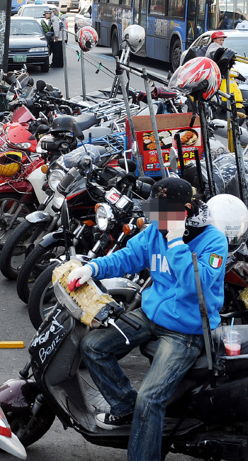 서울 동대문시장 근처에서 배달 노동자가 오토바이에 앉아 대기하고 있다. 배달에 쓰이는 오토바이들이 줄지어 주차돼 있는 모습도 보인다. 경향신문 자료사진