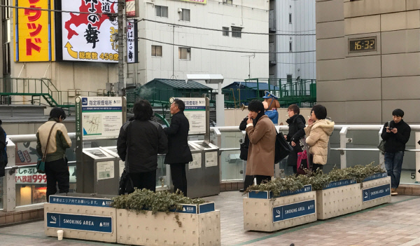 일본 도쿄 아다치구 기타센쥬역 앞에 설치된 흡연소에서 사람들이 담배를 피우고 있다.