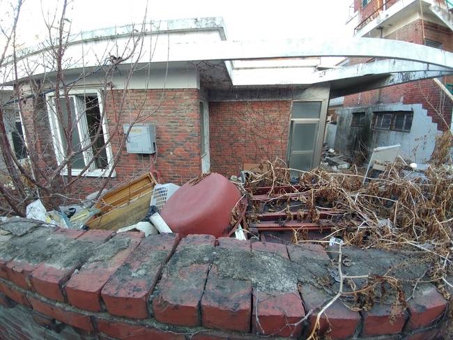 인천 남구 숭의동 인천남중학교 뒷담에 기댄 골목의 한 빈집. 붉은색 고무대야, 부서진 가구 등이 파리한 나뭇가지와 함께 집 마당에 널렸다. 담벼락 일부는 불에 그슬렸다.