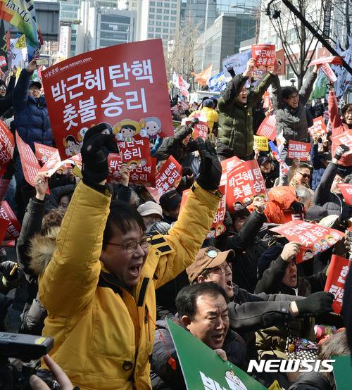 【서울=뉴시스】홍찬선 기자 = 헌재가 박근혜 대통령의 탄핵을 인용을 결정했다. 즉 사상 첫  탄핵심판으로 파면당한 대통령으로 기록되게 됐다.   10일 오후 서울 종로구 헌법재판소 앞 도로에서 박 대통령의 탄핵 인용 소식에 시민들이 피켓을 들고 기뻐하고 있다. 2017.03.10.    mania@newsis.com