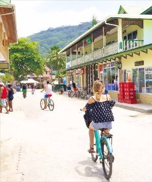 라디그 섬의 번화가를 자전거로 돌고 있는 여행객.