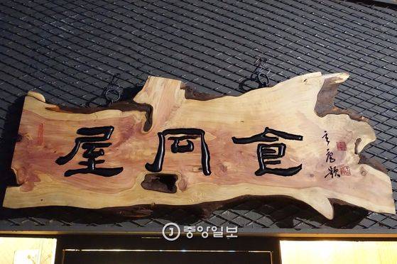 100년 묵은 향나무에 새긴 간판. 현암 정상옥 선생의 휘호를 목우 조정훈 선생이 새겼다. 옥호 ‘옥동식(屋同食)’에는 오너셰프 옥동식씨의 음식철학이 담겼다.