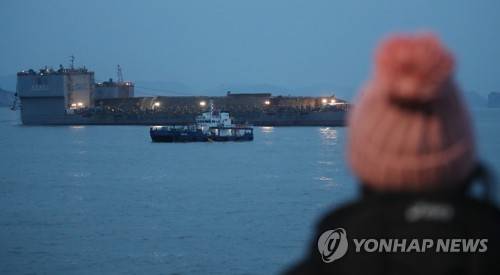 (진도=연합뉴스) 이진욱 기자 = 24일 오후 전남 진도군 사고 해역에서 미수습자 가족이 세월호가 잭킹바지선과 예인선의 도움으로 반잠수선으로 이동하는 것을 보고 있다.       cityboy@yna.co.kr
