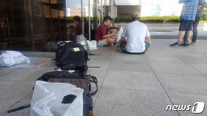 6일 서초동 서울중앙지법 정문에 이재용 삼성전자 부회장 재판의 방청권을 받기 위해 모인 시민들이 그늘에 앉아 더위를 식히고 있다. 가방으로 줄을 만들고 자체 번호표를 만들어 붙였다. © News1