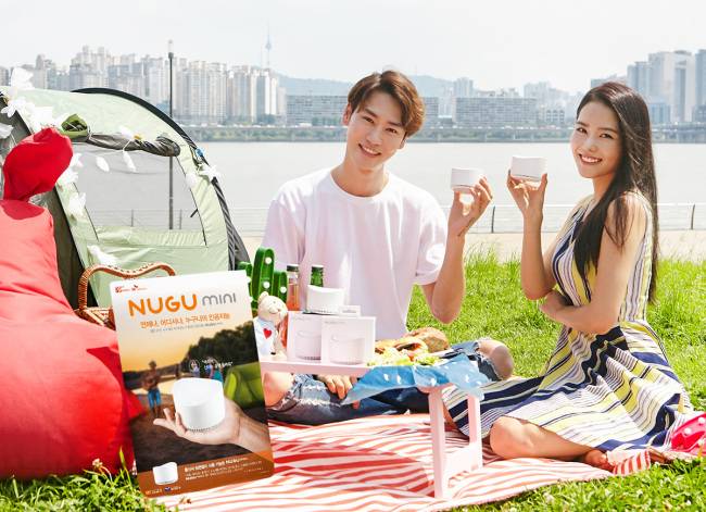 Models hold NUGU Mini devices at a picnic. (SK Telecom)