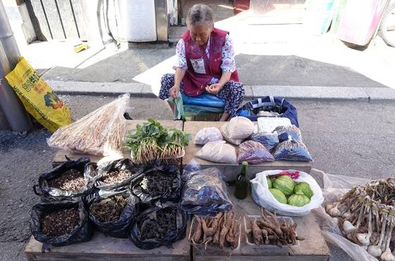 직접 키운 농산물이나 말려둔 산나물을 들고 오일장에 나온 시골 할머니. 가슴에는 ‘신토불이 상인등록증’이 붙어있다.