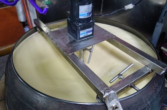 올챙이국수를 뽑기 위해 옥수수가루로 죽을 쑤고 있다. 바닥이 눋지 않도록 저어주는 일은 주걱 대신 모터 달린 기계가 하고 있다.