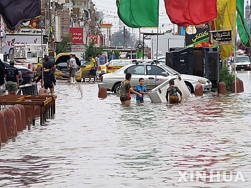 【 바그다드= 신화/뉴시스】이라크 바그다드에 29일(현지시간) 폭우가 쏟아져 홍수가 발생하자 시민들이 물 속에서 집기들을 옮기고 있다. 2015.10.30