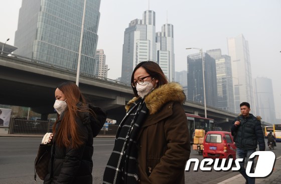 20일 중국 베이징에 스모그 적색 경보가 발령된 가운데 시민들이 마스크를 착용하고 거리를 걷고 있다. 베이징시 당국은 19일 오전 7시부터 22일자정까지 하늘간 대기오염 적색경보를 발령했다. © AFP=뉴스1