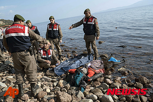 【차낙칼레=AP/뉴시스】30일(현지시간) 터키 서부 해안에서 그리스 레스보스섬으로 가던 난민선이 인근 해안에서 침몰해 어린이 5명을 포함해 최소 39명이 사망했다. 난민선이 침몰한 지역은 터키 서부의 차낙칼레 주 인근 해역이다. 사진은 터키 차낙칼레 아이바즉 해변에 이번 사고로 사망한 난민들 시신이 파도에 떠밀려 와 그 주변에 터키 해안경비대들이 모여있는 모습이다. 2016.01.31.