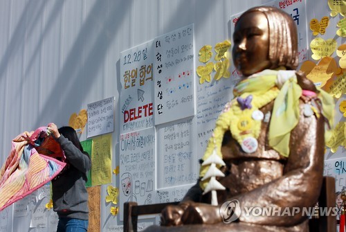 2016년 4월 4일 '한일 위안부 합의 폐기'를 주장하는 팻말들이 나붙은 가운데 서울 종로구 구 주한일본대사관 앞에 평화의 소녀상이 스카프를 두르고 있다.   [연합뉴스 자료사진]