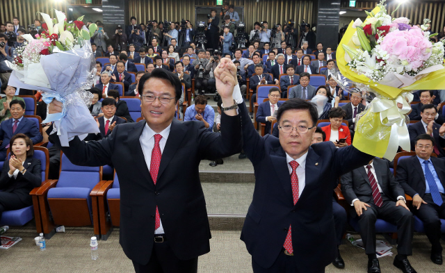 3일 오후 새누리당의 새 원내대표와 정책위의장으로 선출된 정진석(왼쪽), 김광림 당선자가 국회에서 축하 꽃다발을 들고 손을 올리고 있다. 공동취재사진