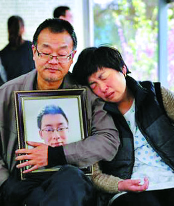 지난달 13일 중국 산시성 셴양의 한 장례식장에서 웨이쩌시의 부모가 웨이쩌시의 영정사진을 안고 흐느끼고 있다. 차이신