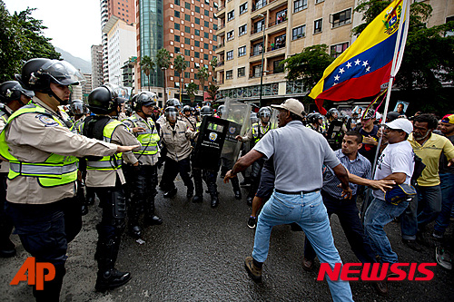 【카라카스=AP/뉴시스】베네수엘라 카라카스에서 18일(현지시간) 니콜라스 마두로 대통령의 퇴진과 새로운 대통령 선거 실시를 요구하는 반정부 시위대가 경찰과 대치하고 있다. 2016.05.19