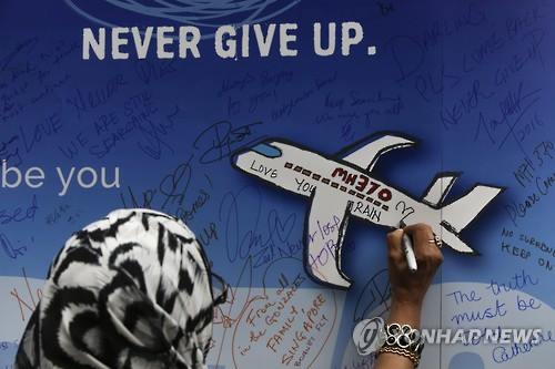지난 3월 말레이시아항공 MH370편 실종 2주년을 맞아 쿠알라룸푸르에서 한 여성이 수색이 계속되기를 희망하는 글을 남기고 있다.<<EPA=연합뉴스 자료사진>>