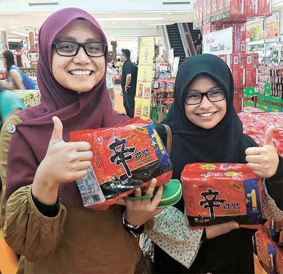 말레이시아 이온 마트에서 소비자들이 농심의 ‘할랄 신라면’을 들어보이고 있다. [사진 각 업체]