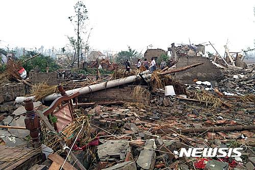 Residents pass houses destroyed in the aftermath of a tornado that hit Funing county, in Yancheng city in eastern China's Jiangsu Province on Thursday, June 23, 2016. A powerful tornado killed dozens and destroyed large numbers of buildings Thursday in the eastern Chinese province of Jiangsu, state media reported. (Color China Photo via AP) CHINA OUT