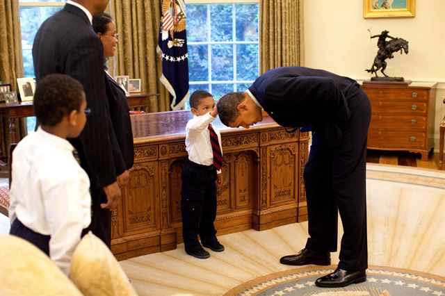 2009년 5월 미 워싱턴 백악관의 대통령 집무실을 방문한 참모진의 아들이 허리를 구부린 버락 오바마 미국 대통령의 머리를 쓰다듬고 있다. 백악관 홈페이지