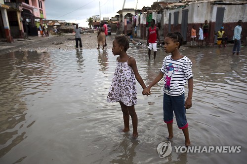 지난 6일(현지시간) 허리케인 매슈가 강타한 아이티의 서남 해안 항구도시 레카예스에서 두 소녀가 물이 들어찬 거리에서 손을 잡고 서 있다. [AP=연합뉴스]