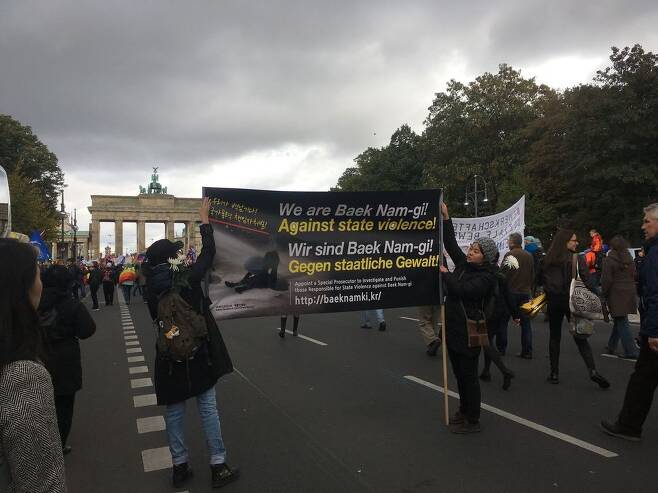8일 독일 베를린에서 열린 반전 시위에 한국 교민들이 ‘우리는 백남기(농민)에 대한 국가폭력을 반대한다’고 적힌 팻말을 펼쳐 보이고 있다. 한주연 통신원