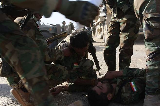 20일 이라크 모술 인근의 바시카에서 이슬람국가(IS)와 교전하던 쿠르드민병대의 한 병사가 총에 맞아 쓰러지자 동료들이 모여들고 있다. 총에 맞은 병사는 현장에서 사망했다.