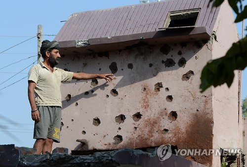 24일 인도령 카슈미르 국경 지역인 카나차크에서 한 인도 주민이 건물 외벽에 총격으로 인한 탄흔을 보여주고 있다.[AFP=연합뉴스]